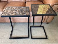 Both square side tables are shown side by side on carpet in front of a leather couch, displaying their metal frames and mosaic tops.