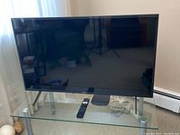 Sony 43-inch KD-43X80J television powered off on a glass table with remote on table in front.
