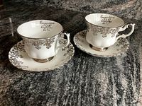 Two Royal Albert tea cups with matching saucers placed on a granite countertop showing front and side views.