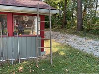 Full view of the entire rustic ladder leaning against a building, showing its full 6-rung length and weathered wood.