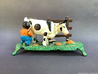 Side view of the cast iron mechanical bank showing man milking cow