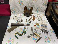 Full lot displayed on a floral cloth background including large carved dog mask, Viewmaster reels, vintage sharpening tool, figurines, tins, medals, and toys.