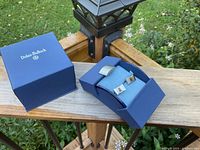 Dolan Bullock original blue presentation box with pair of cufflinks inside, on outdoor wood surface