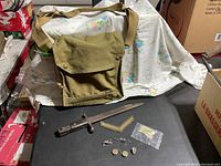 Overview of the canvas bag, bayonet, and various pins and badges displayed on a black surface