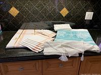 Overview of brand new salmon pink damask tablecloth and napkins on black tiled counter, folded neatly with ribbon on napkins.