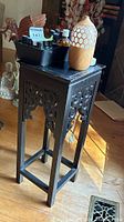 Photo of black wooden side table stand with aromatherapy items on top including diffuser and assorted scented oils in a plastic tray