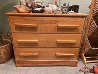 Front view of the wood dresser showing three drawers and wooden handles with visible wood grain and smooth finish.