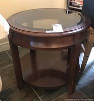 Side view of the round wood end table showing the legs and lower shelf