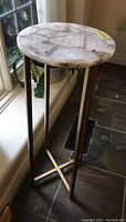 Side view of round marble top stand with wrought iron base, showing the stand's height and leg design