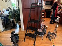 Mastercraft folding step ladder fully opened showing its black plastic steps and metal frame in a home interior.
