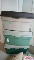 Three stacked plastic storage bins in off-white with brown lid, light green, and dark green.