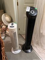 Photo showing two tower fans side by side: one black Seville Classics and one white Natridy.