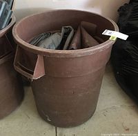 Brown plastic trash bin with lid, showing overall size and condition.