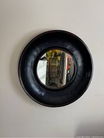 Front view of the round wall mirror with thick black frame mounted on wall.