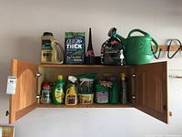 Full front view of wooden cabinet with two open doors revealing gardening and yard care products including various bottles, sprays, and a watering can.