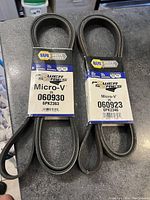 Photo showing two new NAPA Power Series Micro-V serpentine belts side by side with packaging labels visible showing part numbers 060930 6PK2363 and 060923 6PK2346.