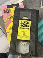 Top view of The Black Crowes VHS tape with visible yellow label and black casing, placed on top of the album cover.