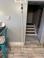 Full view of extension pole leaning against the wall, showing length and overall condition