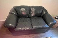 Full front view of the forest green vinyl loveseat showing two seat cushions and large armrests