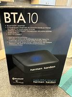 Front of box showing Harman Kardon BTA 10 Bluetooth adapter branding and main features including streaming from Bluetooth-enabled phone or tablet, Harman TrueStream technology, and easy connection.