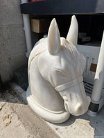 Front and side angled view showing details of the horse head sculpture, smooth white finish, and base.