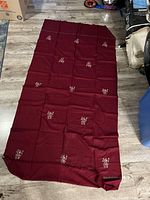 Full view of burgundy linen tablecloth spread on floor showing overall size and embroidered floral design pattern.