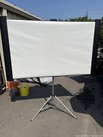 Front view of the movie projector screen fully extended on tripod stand outdoors.