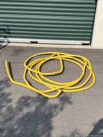 Yellow corrugated flexible natural gas piping coiled on the ground in front of a storage door.