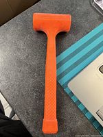 Top view of the dead blow hammer showing the orange handle and head on a kitchen counter.