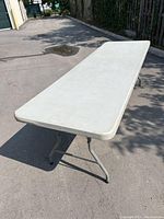 Photo of the folding table set up outdoors, showing the full length and metal legs.