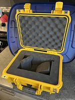 Open yellow Pelican case showing grey foam insert with custom cutouts to fit an instrument or equipment securely.