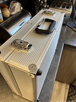 Close-up of silver aluminum hard case corner with latch and handle.