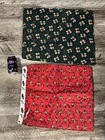 Photo of two quilted Christmas stocking bags laid flat on wooden floor; one red with nutcracker pattern and white border, one green with teddy bear pattern.