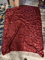 Full view of the deep red rectangular tablecloth laid flat, showing overall size and leaf pattern.
