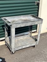 Full view of heavy duty metal utility cart showing two shelves and caster wheels