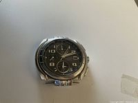 Front view of silver-tone Pulsar watch head with black dial and chronograph subdials.