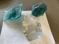 Three distinct Scandinavian art glass sculptures with etchings placed on a light surface.