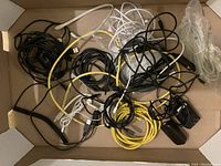 Various cables including USB, ethernet, and audio cables tangled in a box.