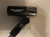 Side view of the Royal Traveller travel hair dryer showing the brand and foldable handle with settings switch.