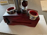 Wine accessory holder with bottle stopper and two metal pourers with red rubber interiors