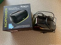 NUPOWER ROKS wireless speaker boxed and outside with attached audio cable visible