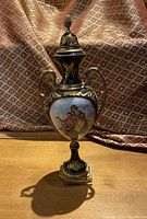 Full view of the urn standing upright showing its shape, colors, and lid finial