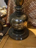 Close-up of bronze lamp base showing Japanese landscape design with gold-tone accents.