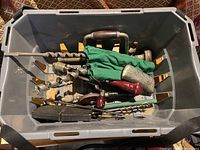 Top down view of the tools inside a plastic crate including drill bits and hand drills.