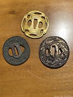 Photo showing all three tsubas together on a wooden surface to display their overall design and size differences.