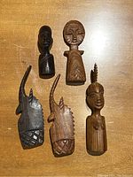 Top view showing all five small wooden tribal figures including two human and three animal representations.
