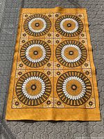 Full view of the rectangular woven carpet with six large sunburst circle patterns on a mustard yellow background, showing overall condition and design.