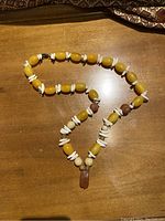 Full view of the amber and shell bead necklace laid out on a wooden surface.