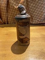 Front view of cylindrical bamboo ornament with carved wolf design on the surface.