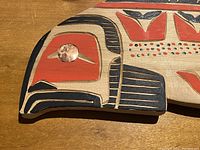 Close-up of the carved salmon head showing painted design and eye detail with copper or metallic accent.